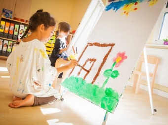Kind malt mit Pinsel und Farbe an Staffelei