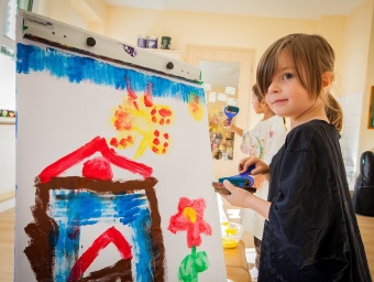 Kind malt mit Farbrolle an der Staffelei