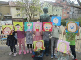 Kinder halten ihre Selbstporträts vor ihr Gesicht