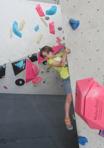 Ein Junge hält sich an den Bouldergriffen fest