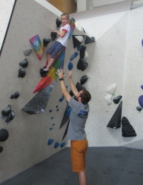ein Kind klettert an der Boulderwand hoch