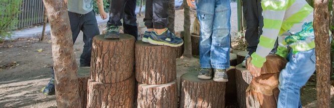 Kinder stehen auf kleinen Holzpflöcken und spielen