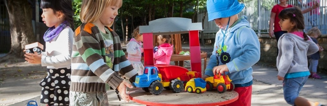 Kinder spielen mit Baufahrzeugen im Sand